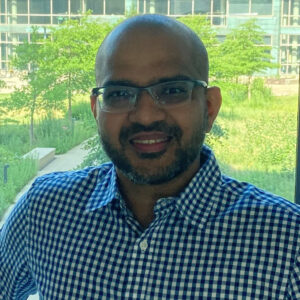 Dr. Pratyush Suryavanshi is standing inside the university building, with numerous plants visible behind him