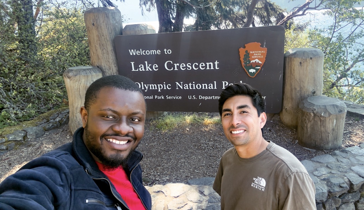 Photograph of two graduate students in front of a National Park Services sign for Lake Crescent in Olympic National Park