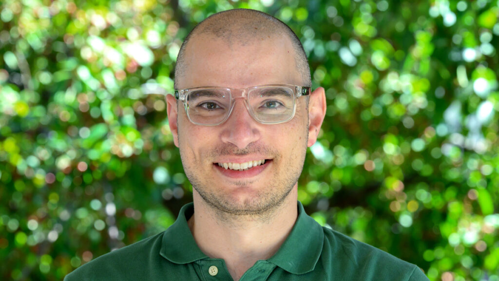 Dr. Eleftheriou outside with greenery filling the background.