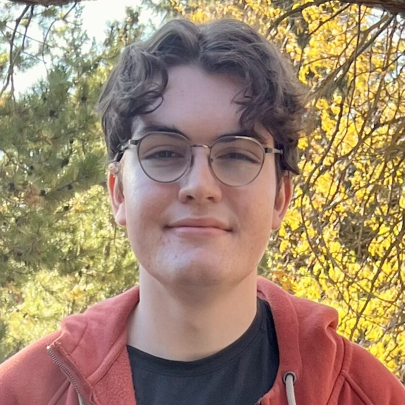 A photo of Samuel Hickman in a red hoody in the nature.