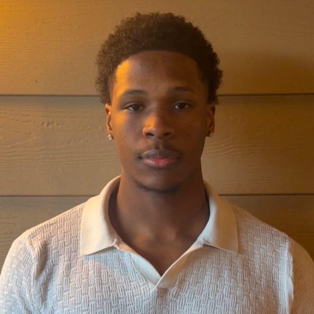 Khalil Abdullah in a white shirt in front of a wooden wall