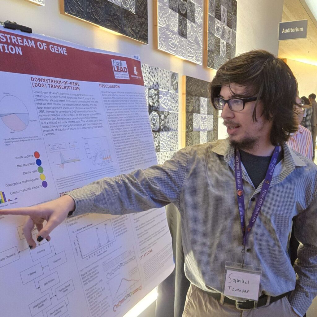 Samuel Toompas in purple shirt pointing to a poster