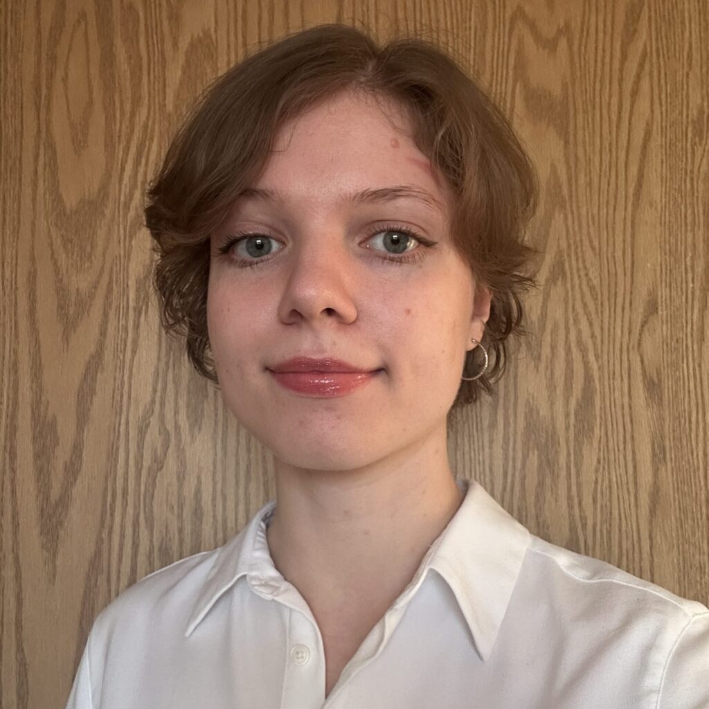 Anastasia Chepel in a white shirt in front of wooden background