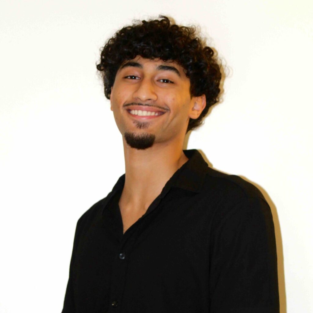 Abdelrahman (Bodi) Abdelrazek in a black shirt smiling in front of white background