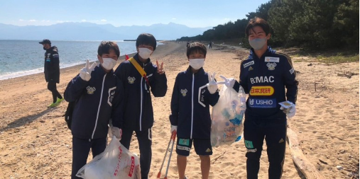 four people on a beach picking up trash