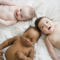 3 babies lying on a white blanket