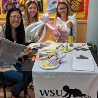 Research students at an event table with balloons