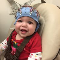 Baby sitting in chair with blue cap on