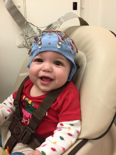 Baby sitting in chair with blue cap on