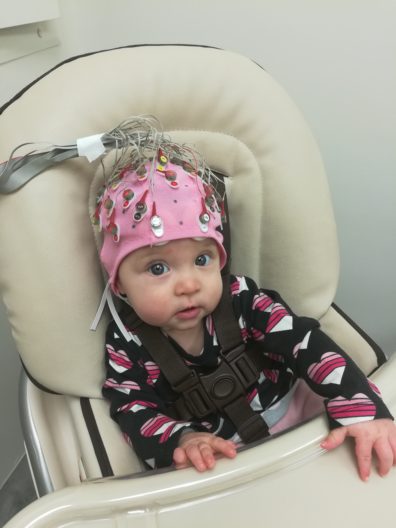 Baby girl in high chair wearing pink lab helmet