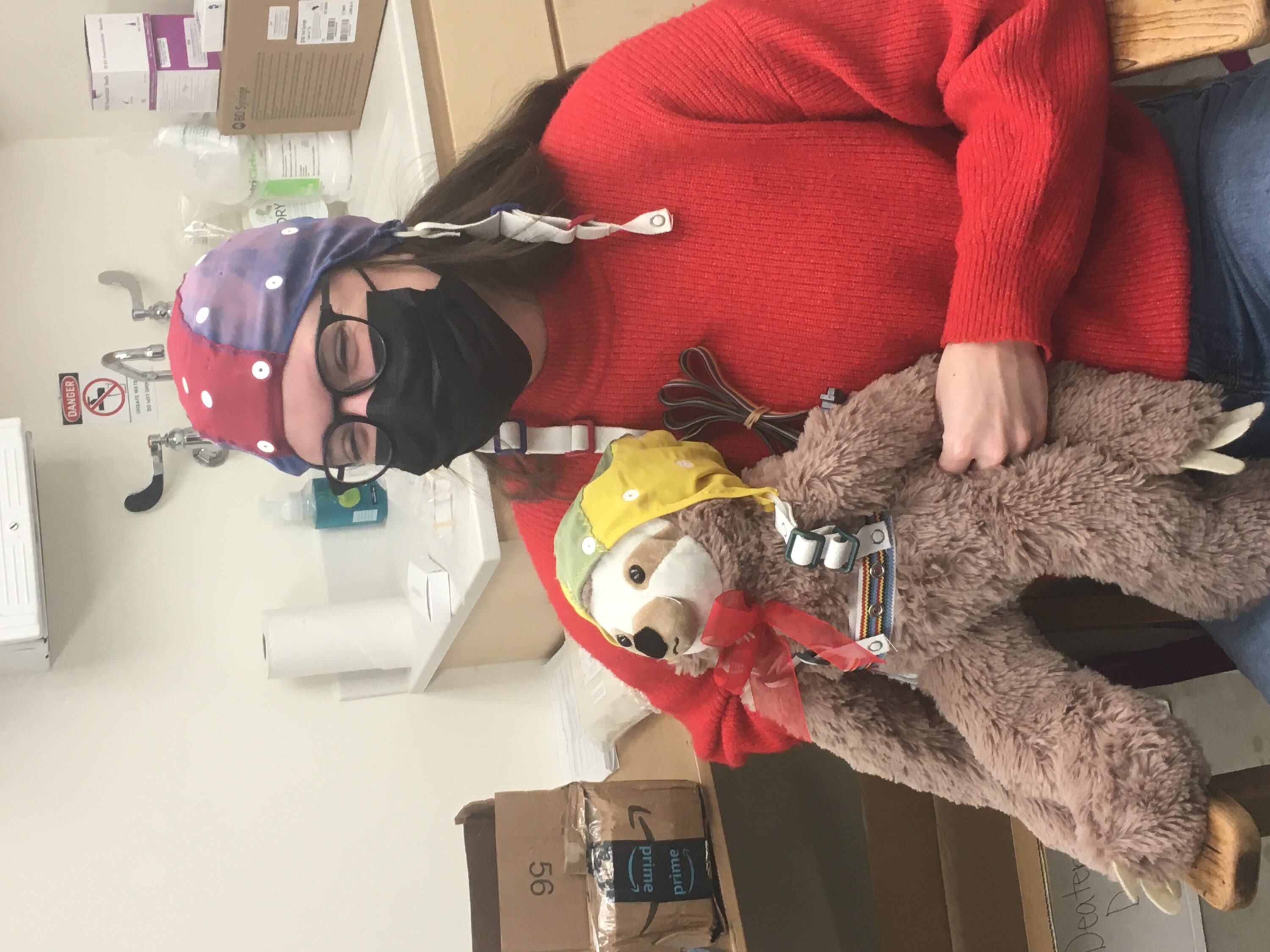 Student researcher in research cap holding a stuffed animal