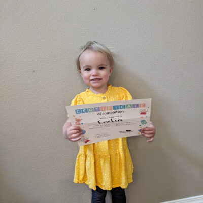 Female toddler in yellow dress holding a certificate