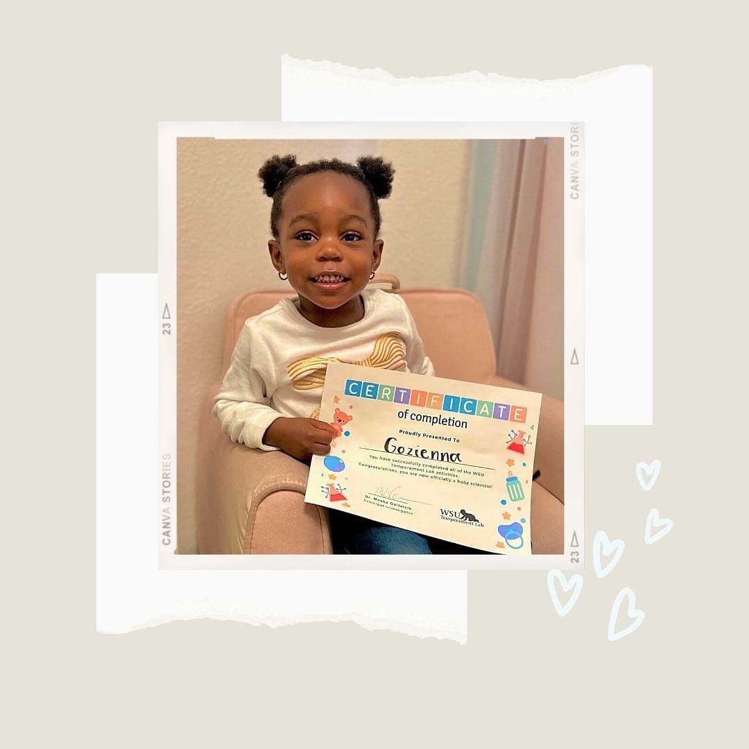 African-American girl sitting in pink chair holding a certificate