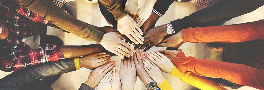 Group of many people in circle from overhead with hands pointing toward the center.