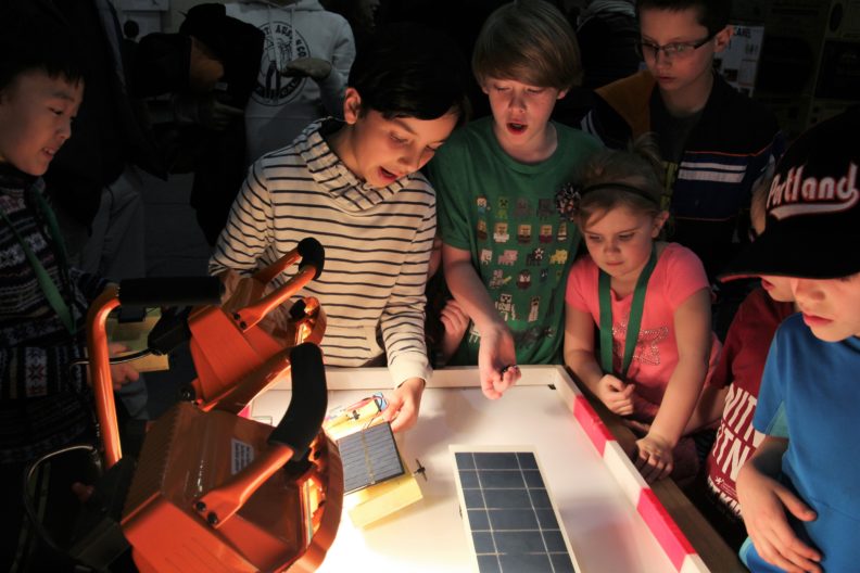 Kids gather at the end of the track to describe the solar cars they constructed.