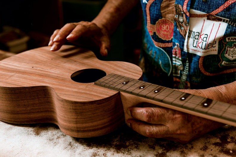 Sam Kamaka Jr. testing the acoustic properties of an unfinished ukulele by tapping on the body, or "tuning the top."