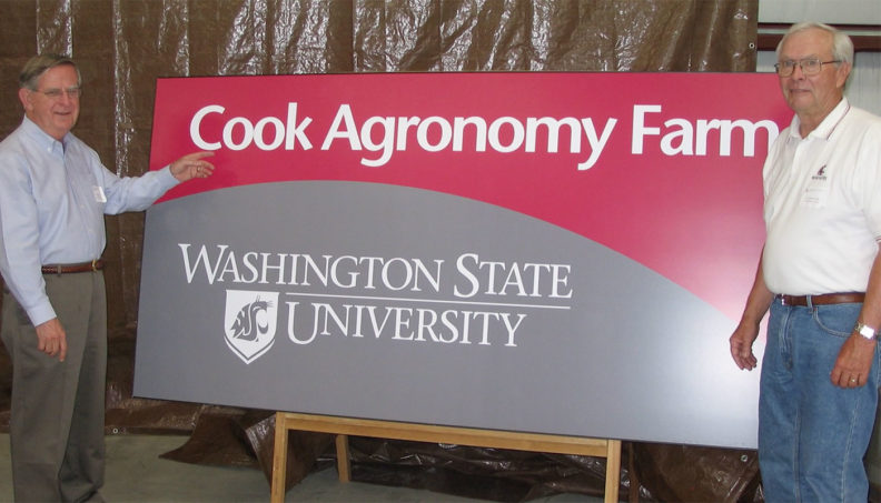 Jim Cook and Sam Smith next to WSU Cook Agronomy Farm sign