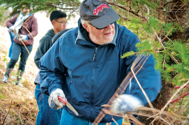 Ed Bassett and Olympia High School students trim trees at Meyer's Point