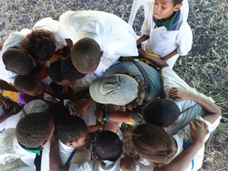Group of kids in Papua New Guinea look at info about birds