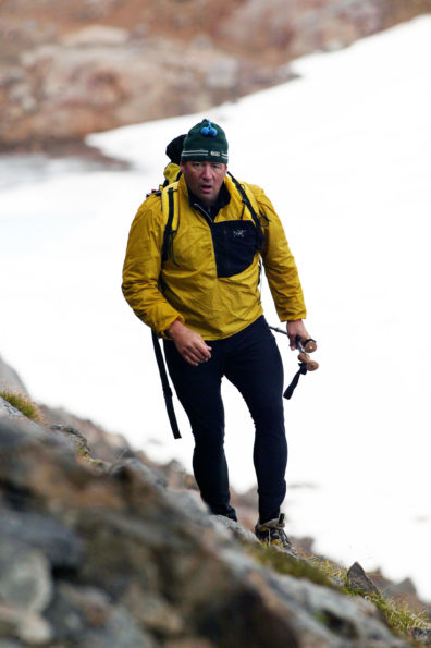 Buddy Levy trekking steep scree slopes above a glacier in Southeastern Greenland.