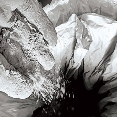 Hand dropping volcanic ash into a bag