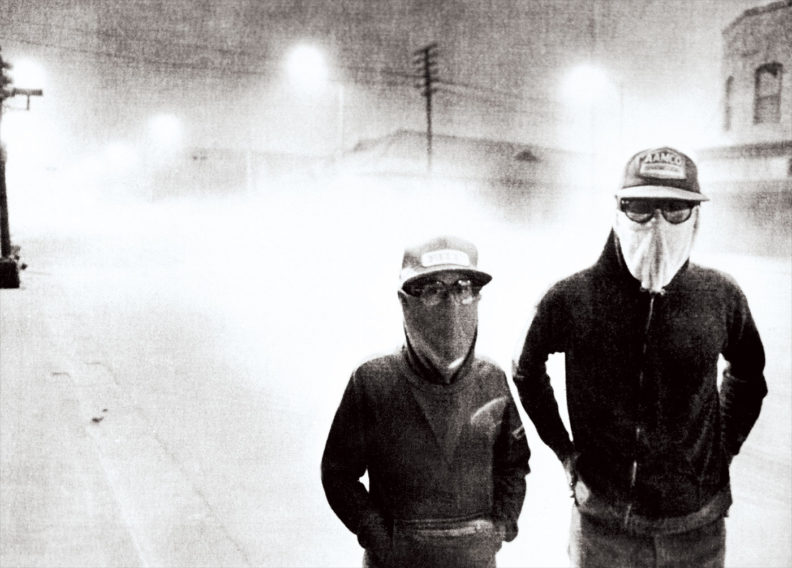 Two people in facemasks walk on a dark street in Yakima after ash from Mount St. Helens eruption in 1980