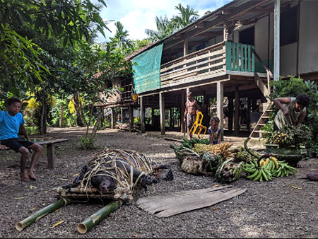 House in Papua New Guinea with fruit, meat and other goods in front