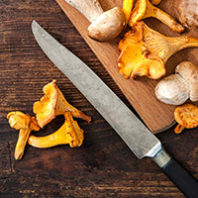 Porcini and chanterelle mushrooms on a cutting board with knife