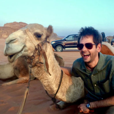 Michael Letko sits next to a camel