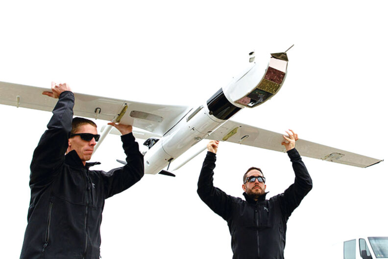 Two men hold up a drone that uses hydrogen fuel