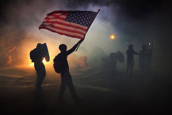 Protestor waves an American flag in the smoke during the 2020 Black Lives Matter protests in Portland, Oregon.