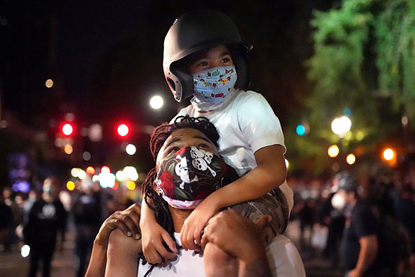 Wall of Veterans PDX organizer Leshan Terry with his son on his shoulders during a 2020 protest in Portland, Oregon
