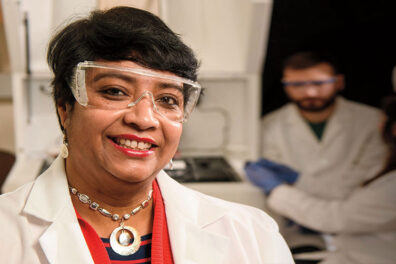 Researchers Susmita Bose in safety goggles and lab coat in her laboratory