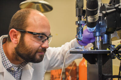 Researcher Arda Gozen looks at a 3D printer as he studies printed cartilage