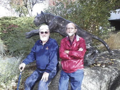 Robert Schorr and Denny Johnston sit on the pedestal next to the WSU cougar statue
