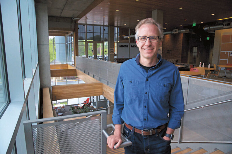 Ryan Smith at Washington State University stands at the top of stairs in the PACCAR Building