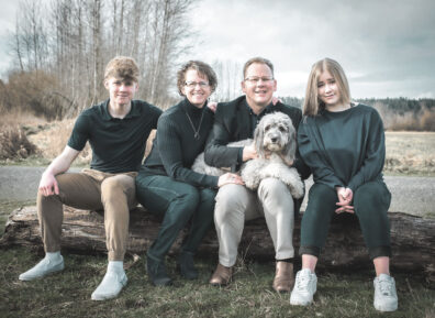 Washington State Superintendent of Public Instruction Chris Reykdal with his family, wife Kim, son Carter, daughter Kennedy, and dog all sit on a log