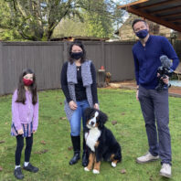 Stacy Slade stands in backyard with her daughter, husband, and Frenzy the dog