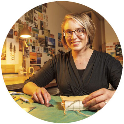 Linnea Rash at Washington State University Pullman at a desk as she restores an old book in the library