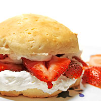 Sliced strawberries and whipped cream on biscuit