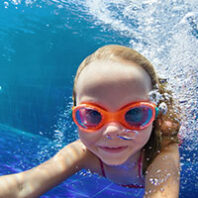 Young girl in goggles swimming in pool