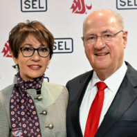 Edmund and Beatriz Schweitzer stand in front of a Washington State University and SEL backdrop