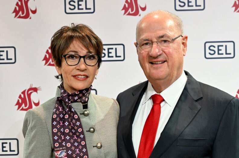 Edmund and Beatriz Schweitzer stand in front of a Washington State University and SEL backdrop