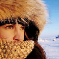 Amanda Boyd wearing hooded winter coat looks at Arctic landscape