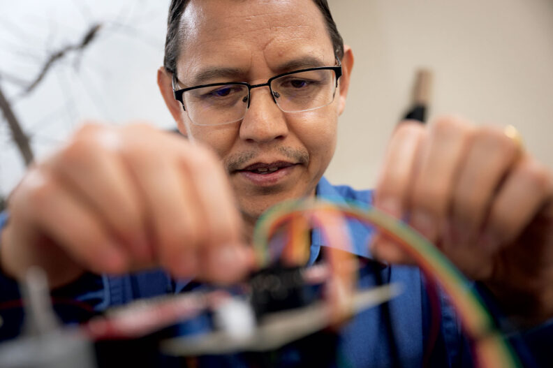 Engineer Manoj Karkee adjusts wires on a robot