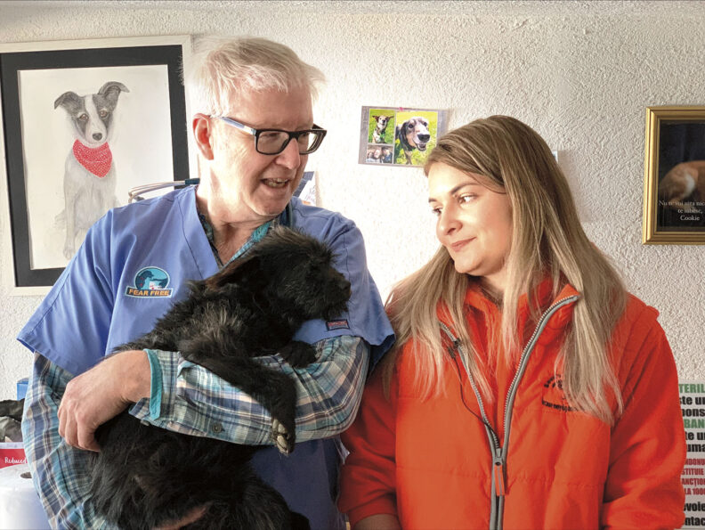 Veterinarian Marty Becker holds a black puppy from Ukrainian refugees at a Romanian shelter, as Alexandra Sava who manages shelter looks on