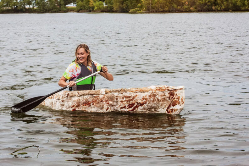 Katy Ayers paddles on a lake in her mycelium canoe