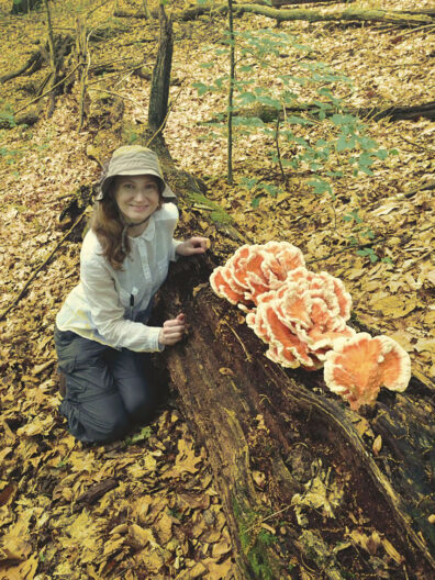 Biologist Tanya Cheeke with fungus on a fallen log