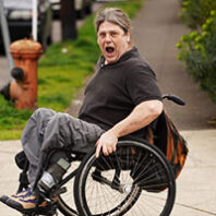 Tom Haig gives a surprised expression while rolling his wheelchair
