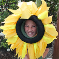 Smiling girl looks through a flower mask